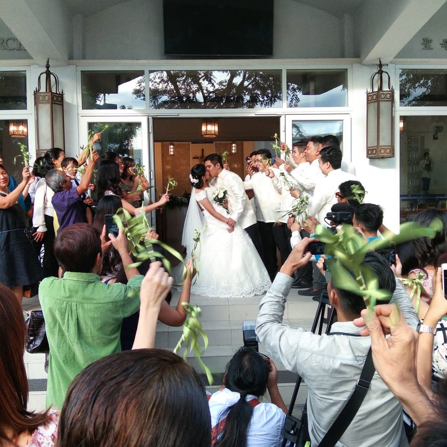 A couple kissing surrounded by their guests